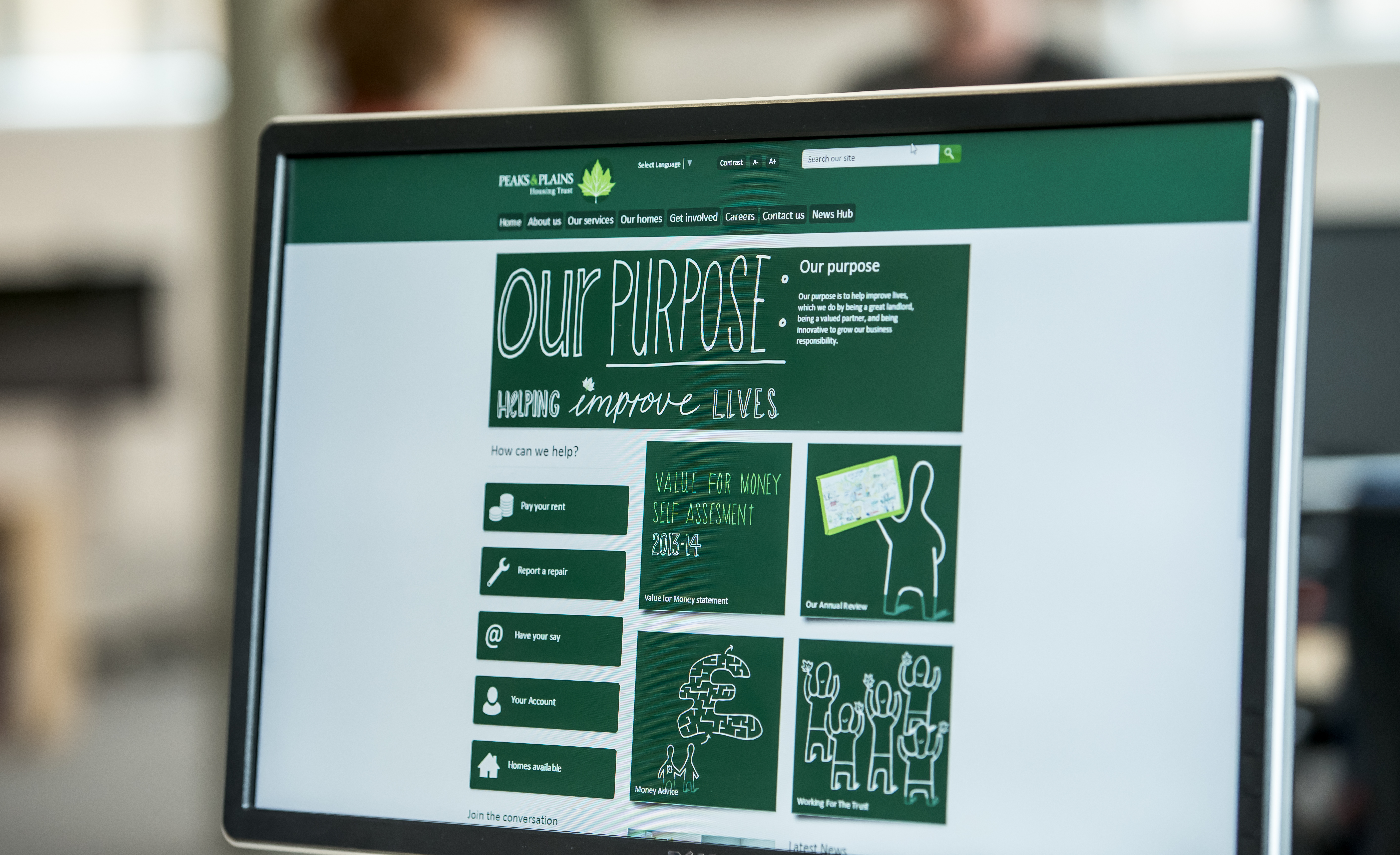 A photo of the Peaks and Plains website homepage shown on a monitor