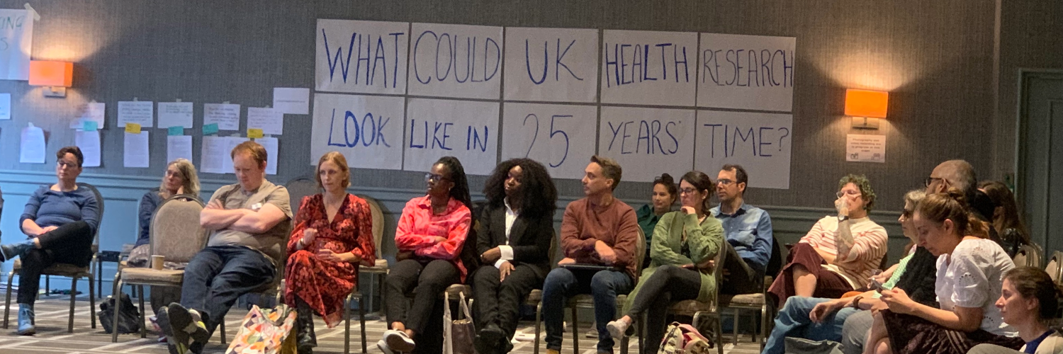 A group of people seated under a sign reading "What could UK health research look like in 25 years time' 