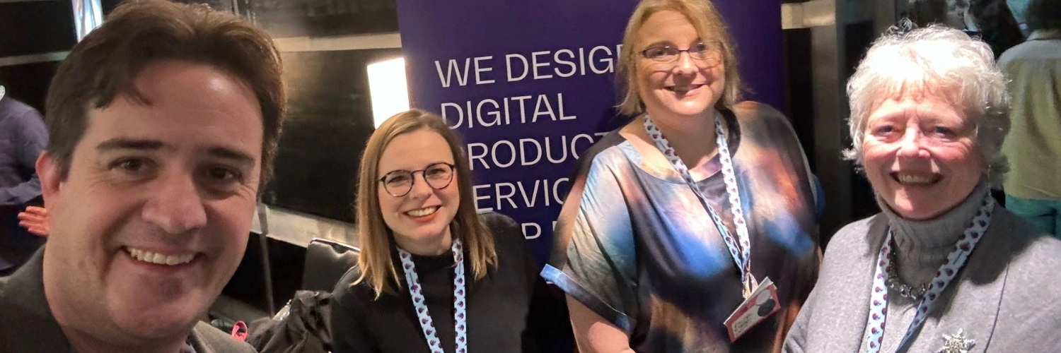 Chris, Burcu, Rachel and Elizabeth smile at the camera in front of a Nexer Digital banner