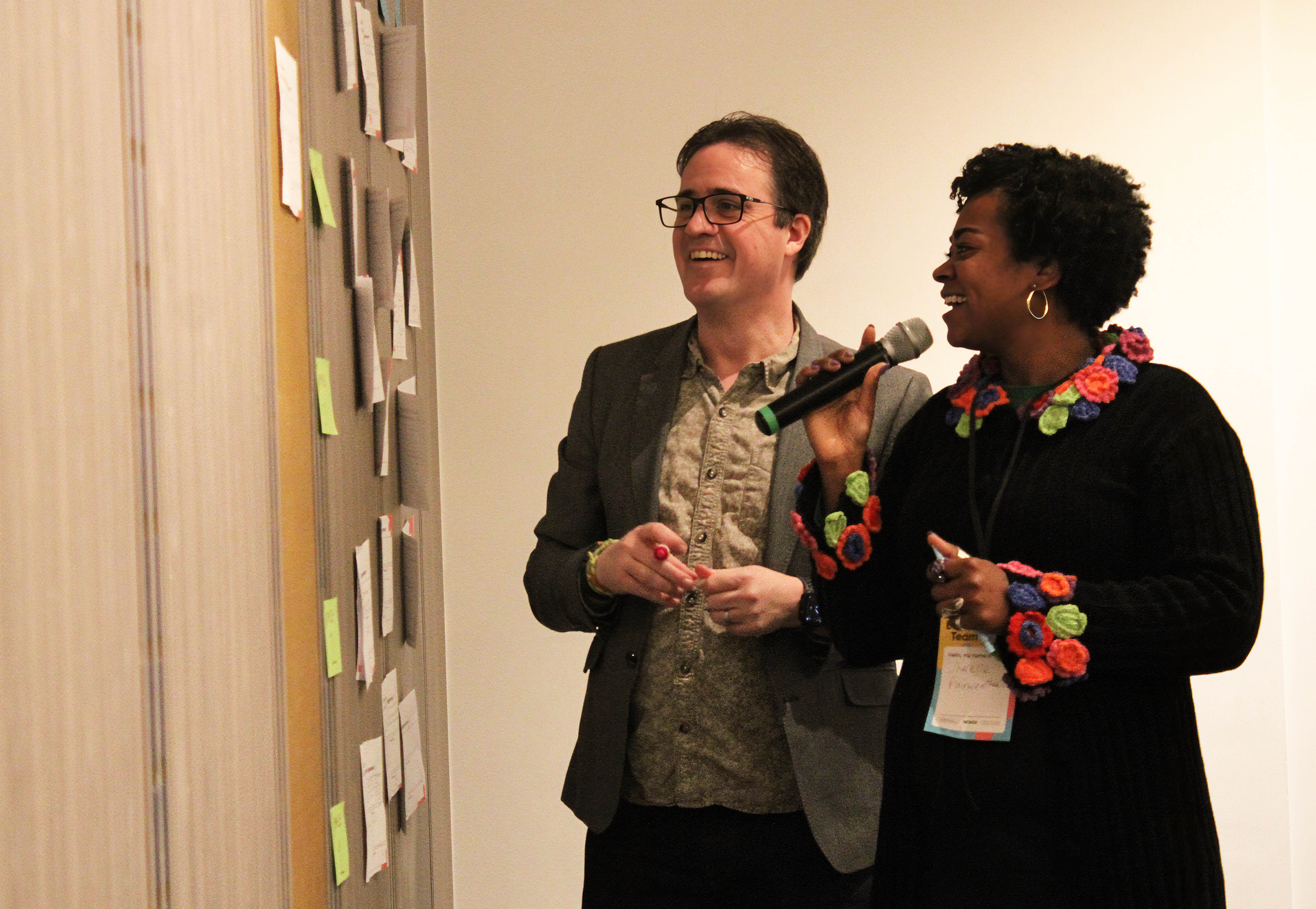 Chris and Sherelle look at the Unconference agenda wall while smiling
