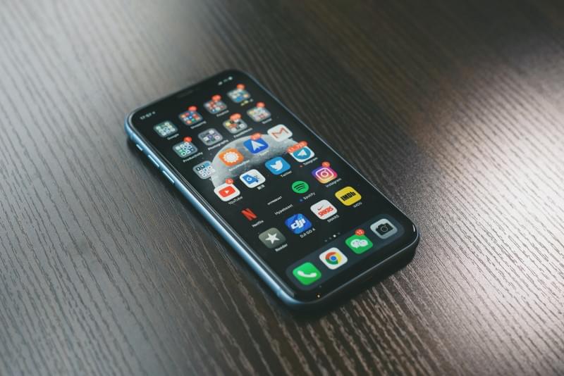 Phone lying on a table showing the home screen with lots of apps with notifications
