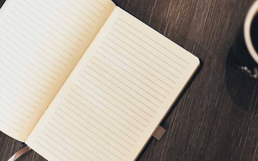 An open diary notebook resting on a dark wooden table