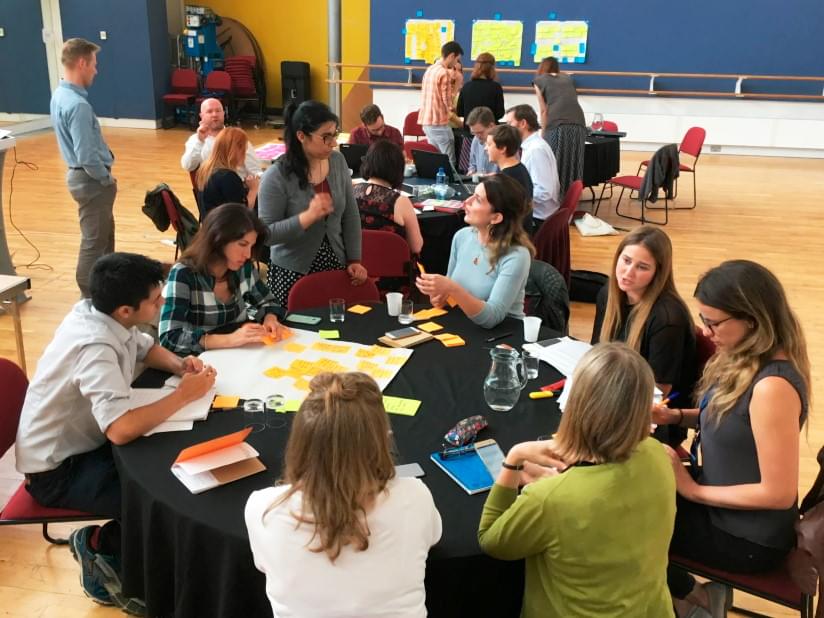 A group of people around a table with lots of post it notes. 