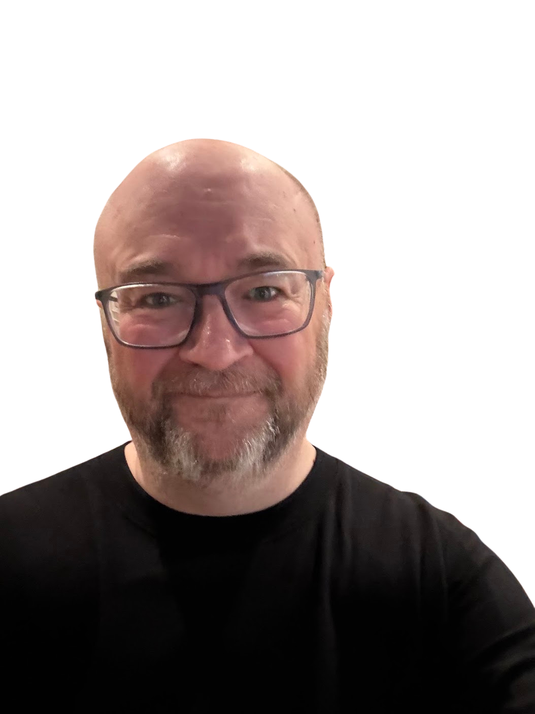 Matt has a shaved head and a beard, is wearing glasses and a black shirt, and smiling broadly at the camera. The background is blurred