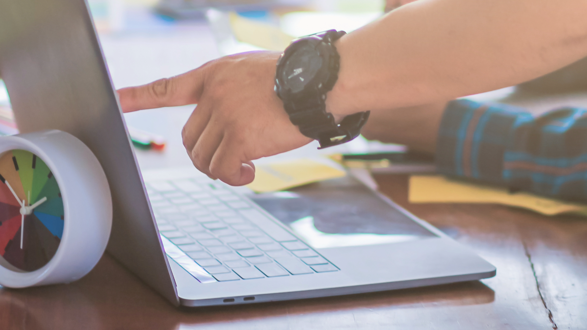 A hand pointing at the screen of a laptop