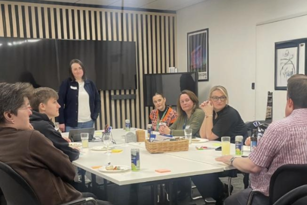 People from Nexer's event with macc pride sit around the table in the conference room, as Sarah Knowles addresses them