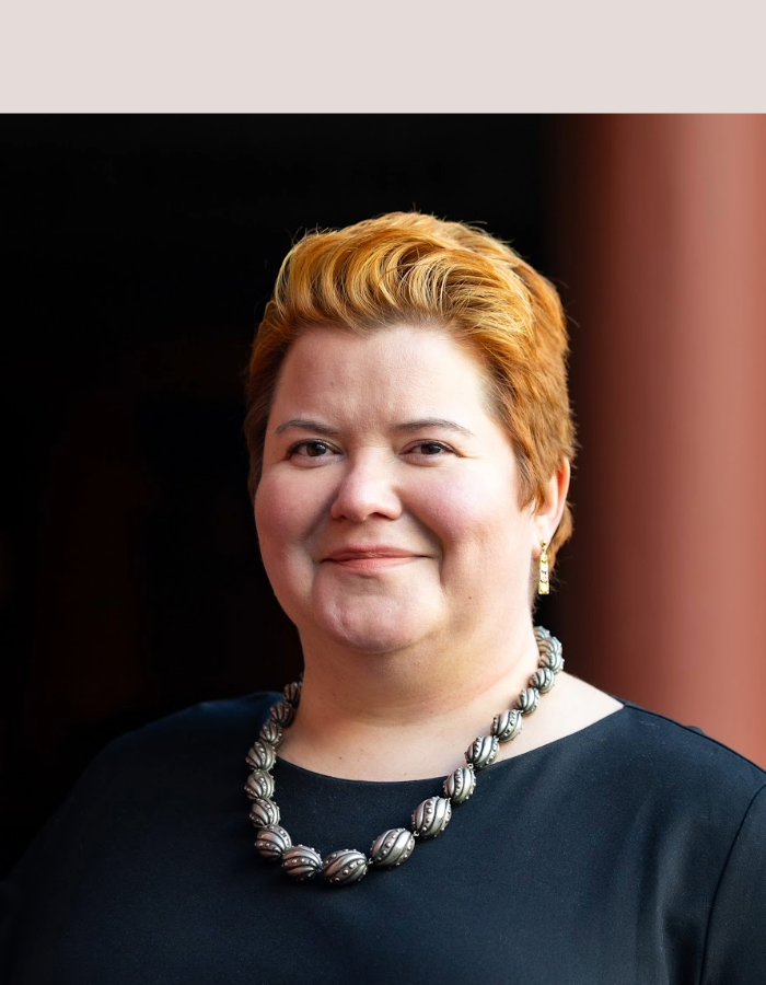 Headshot of Lisa Riemers, Camp Digital 2026 speaker. Lisa has short red hair, and is wearing a black top and beaded necklace.